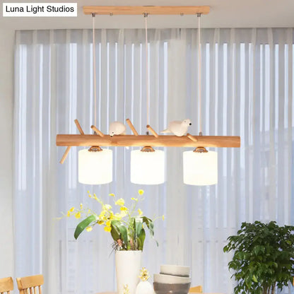 Modern wood cylinder hanging light with white glass shades and bird figurines on natural wood branch design for kitchen