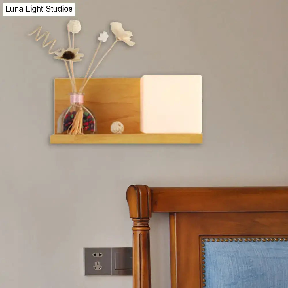 Minimalist wooden floating shelf with warm finish holding dried flowers and a softly glowing beige wall lamp sconce light