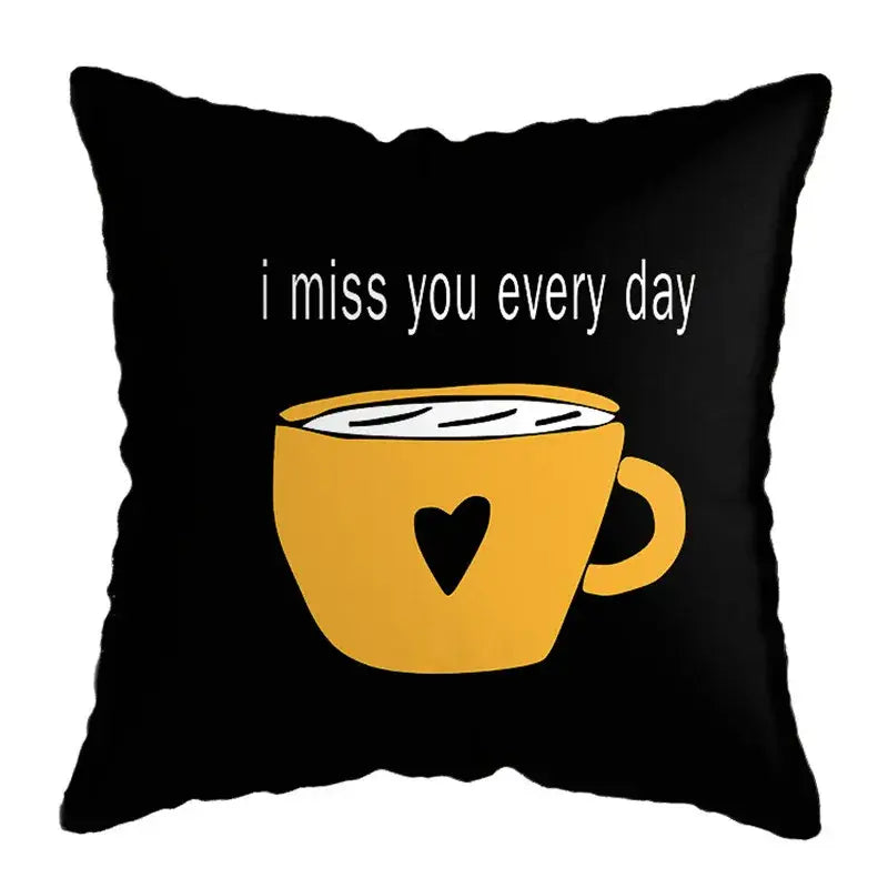 Black throw pillow with yellow coffee cup heart and white i miss you every day text, styled with geometric deer print decor