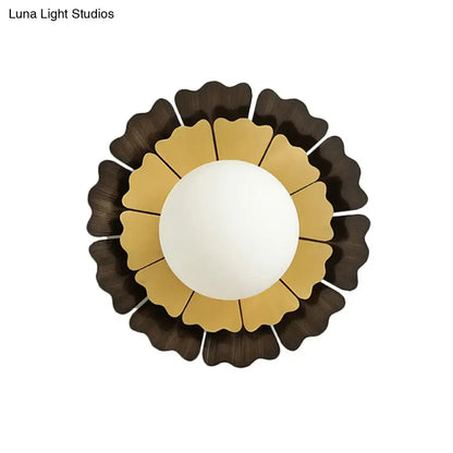 Modern yellow and brown sunflower wall sconce with a white globe and gold and dark brown metal petals for bedroom lighting