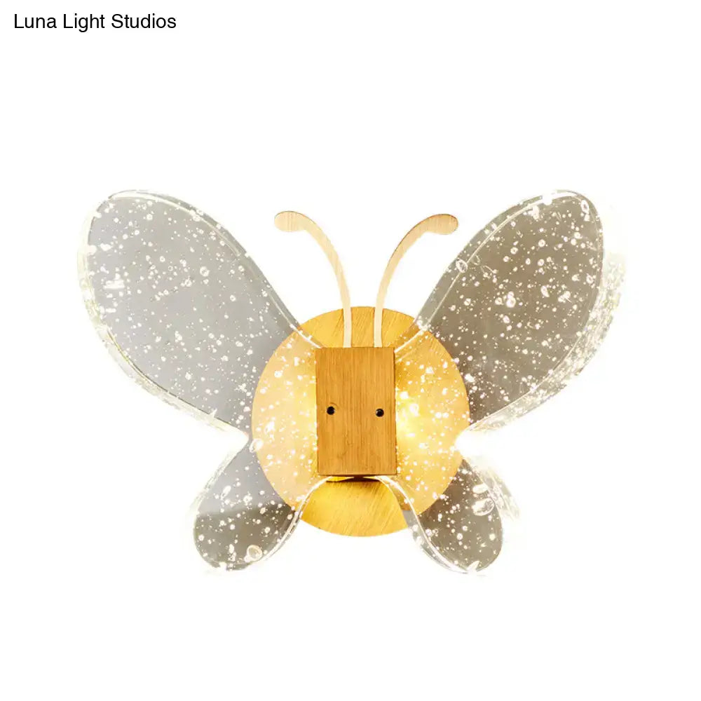 A modern yellow and clear butterfly bubble crystal sconce with translucent gray wings and a warm golden wooden body