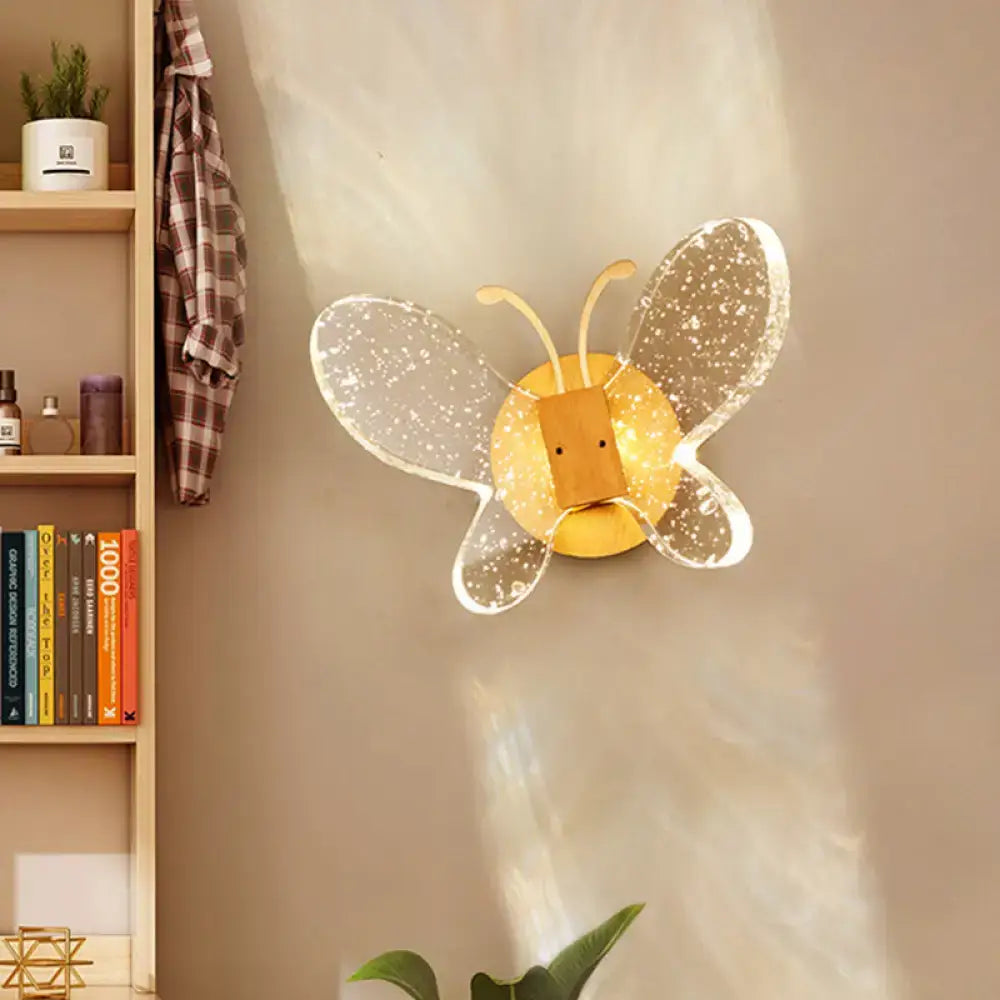 A modern yellow and clear butterfly bubble crystal sconce with sparkling wings for bedroom lighting