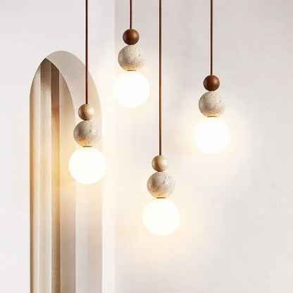 Modern yellow travertine and wood led bulb pendant light with spherical concrete and wood beads suspended by thin cords