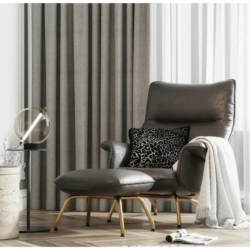 Modern zebra pattern black and cream pillow cover on dark gray leather armchair with gold-tone legs by decorbites gold zebra