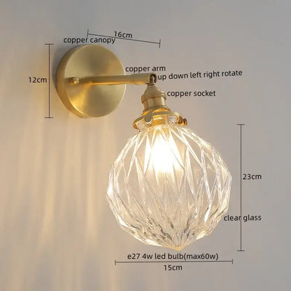 A modern green glass led wall lamp with a clear faceted glass globe and brass copper arm for bedroom lighting