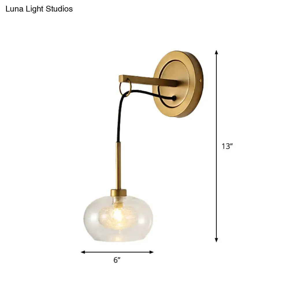Brass-finished modernist wall sconce with amber white glass globe and black cord for bedroom lighting