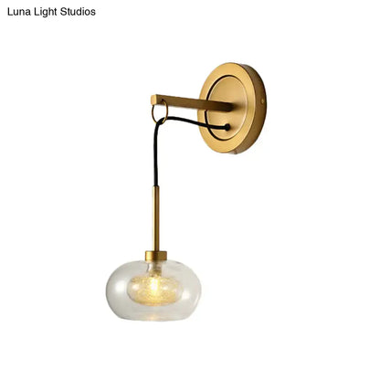 Gold-toned modernist wall sconce with amber white glass globe and black cord for bedroom drop lamp lighting