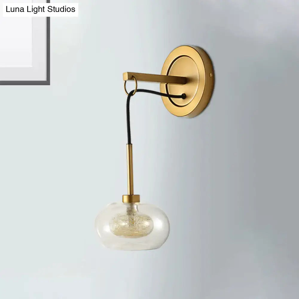 Gold-toned modernist bedroom wall sconce with amber white glass globe and black cord drop lamp