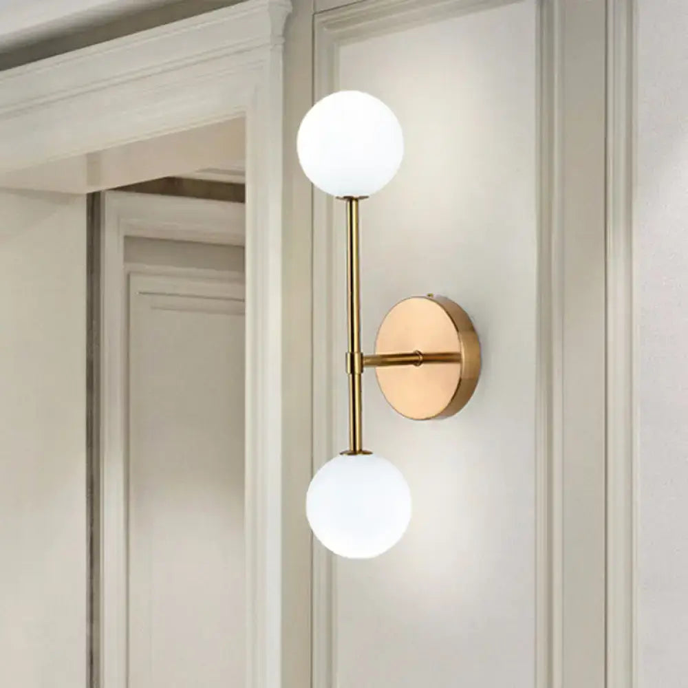 Brass-finished wall sconce with two frosted glass globes in black gold finish for modernist living room lighting