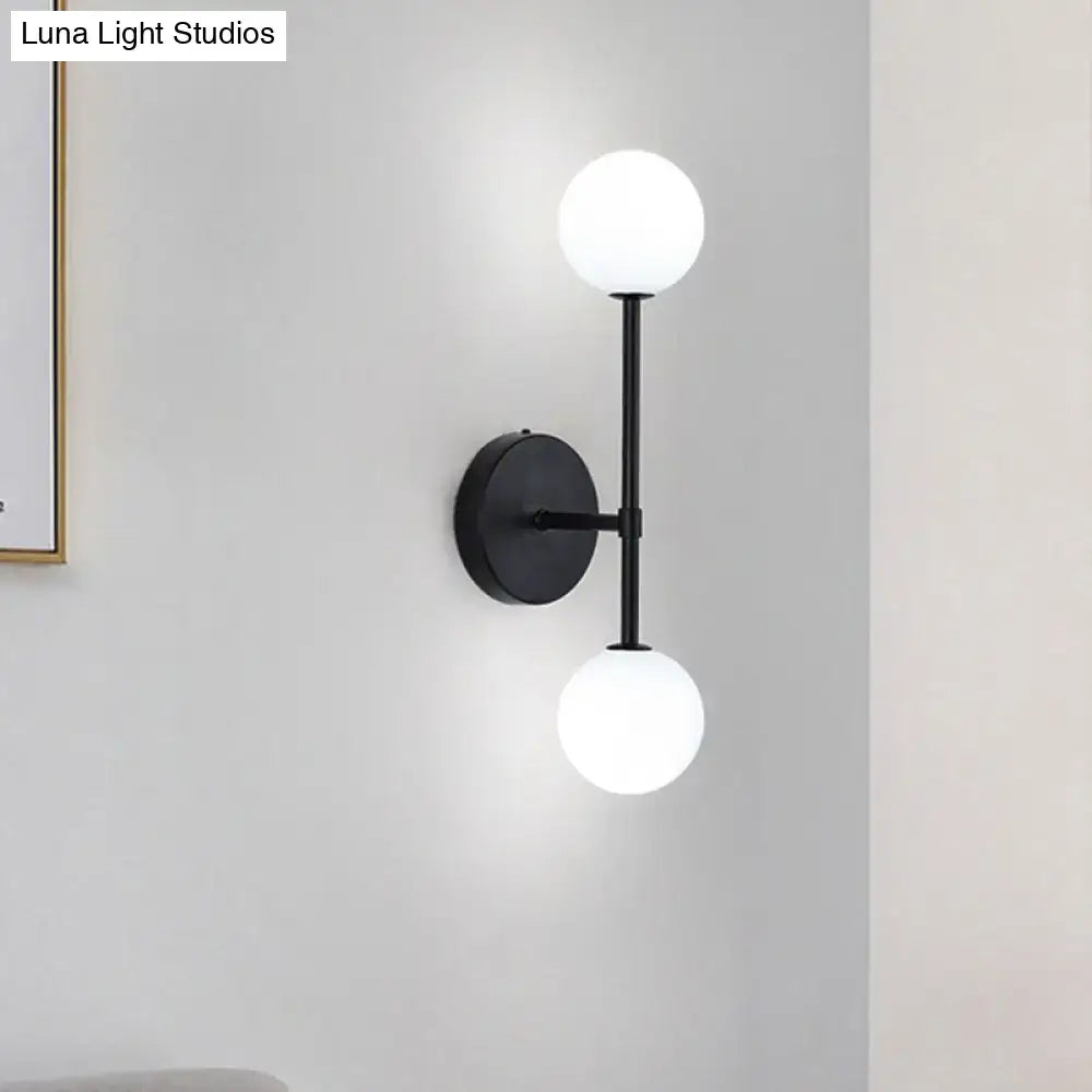 Modernist black metal wall sconce with gold finish and two frosted glass globe shades for living room lighting