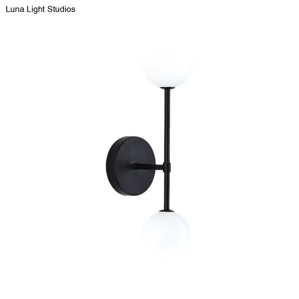 Modernist black gold wall sconce with two frosted glass globe shades and a gold finish for living room lighting