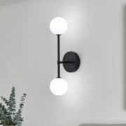 Modernist black wall sconce with gold finish and two frosted glass globe shades for living room lighting