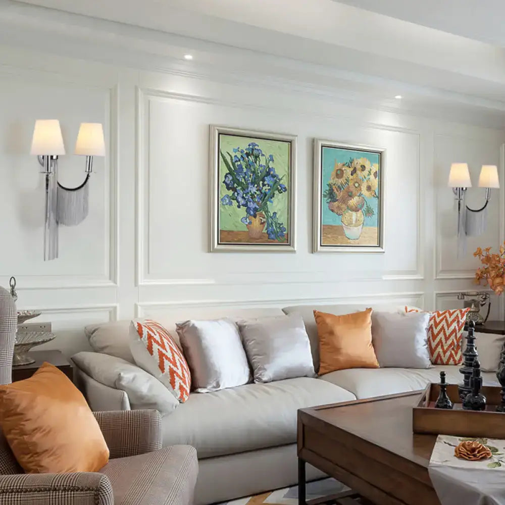 Beige sectional sofa with orange and white patterned throw pillows beside modernist black and silver e12 tassel wall sconce