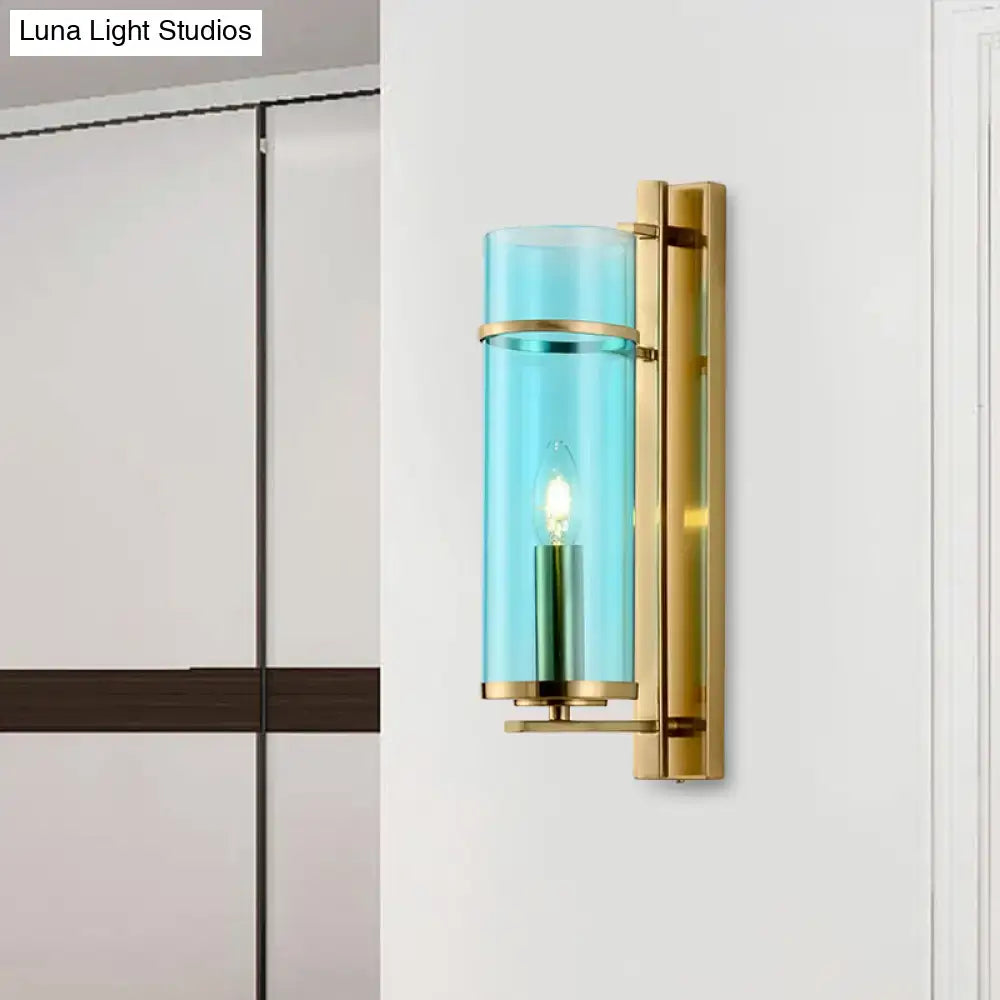 Modernist wall lamp with polished brass hardware and water blue glass cylinder as bedroom sconce light fixture