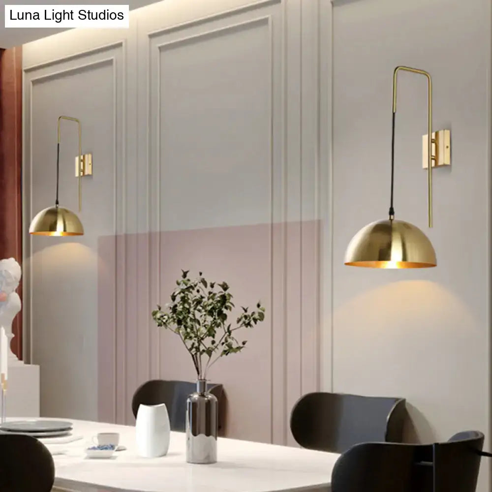 Modernist brass dome sconce wall light featuring curved arm and black cord as a bedroom light fixture