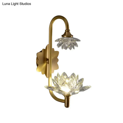 Modernist wall sconce with brass finish featuring two crystal shade lotus flower designs, one illuminated, for bedroom use