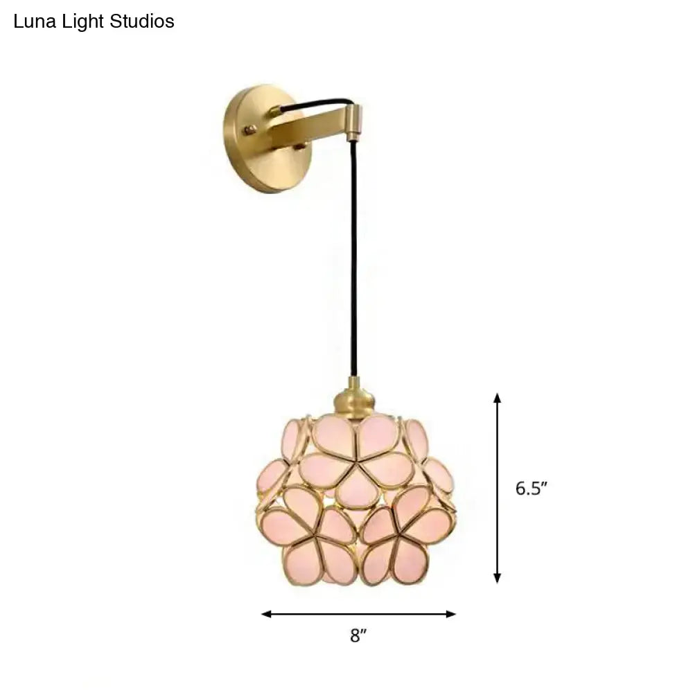 Modernist brass floral glass bulb bedside sconce with a delicate light pink floral pendant and black cord wall mount