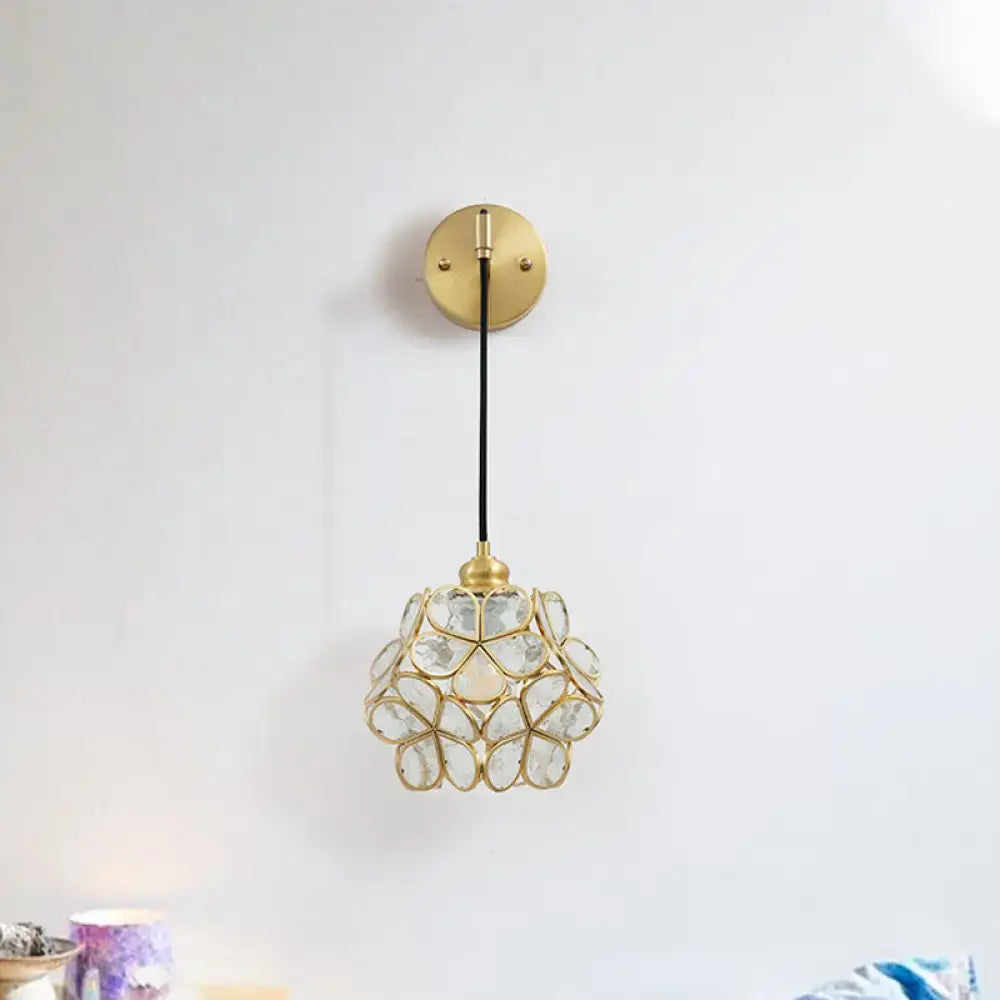 A delicate gold-toned modernist brass floral glass bulb bedside sconce with light pink and clear flower-shaped shade