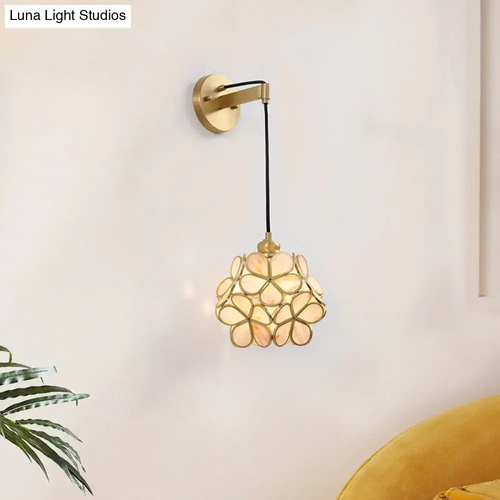 A delicate modernist brass floral glass bulb bedside sconce with light pink and pink clear petal-shaped shade