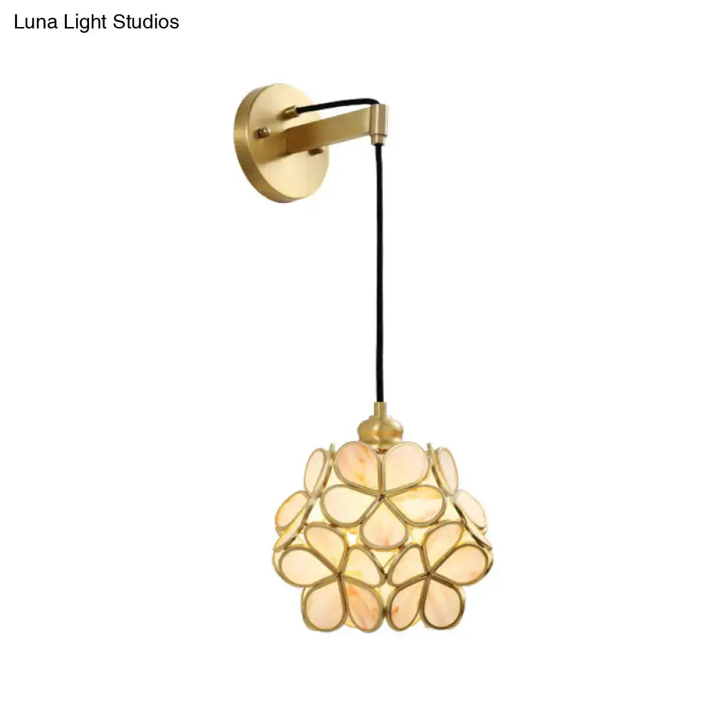 Modernist brass floral glass bulb bedside sconce featuring light pink petal-shaped glass pieces in a cluster design
