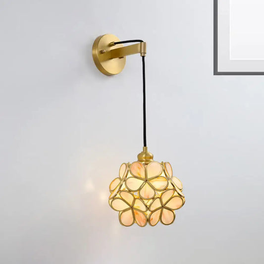 Modernist brass bulb bedside sconce with light pink clear flower-shaped glass shade in peach and amber tones