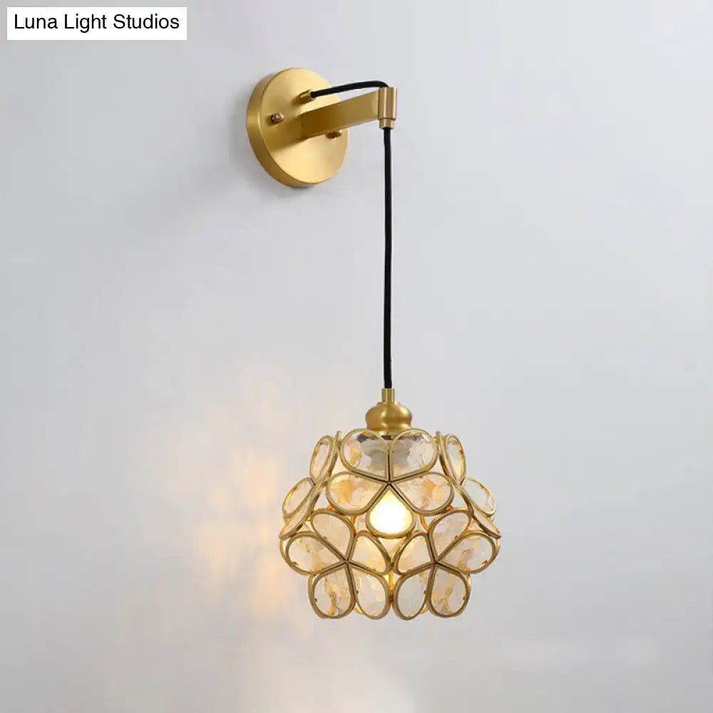 Modernist brass bulb bedside sconce with light pink and clear floral glass shade suspended by black cord