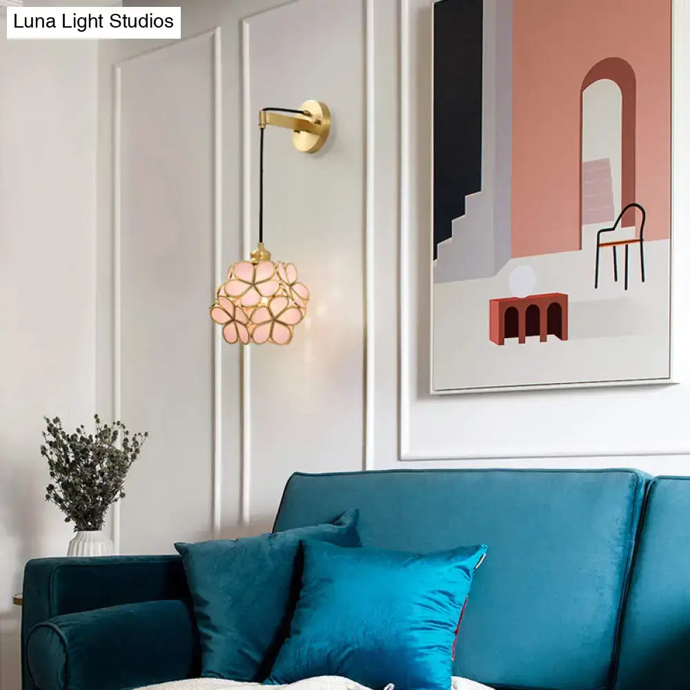 A delicate modernist brass floral glass bulb bedside sconce light pink and clear with gold-toned frame hanging from wall