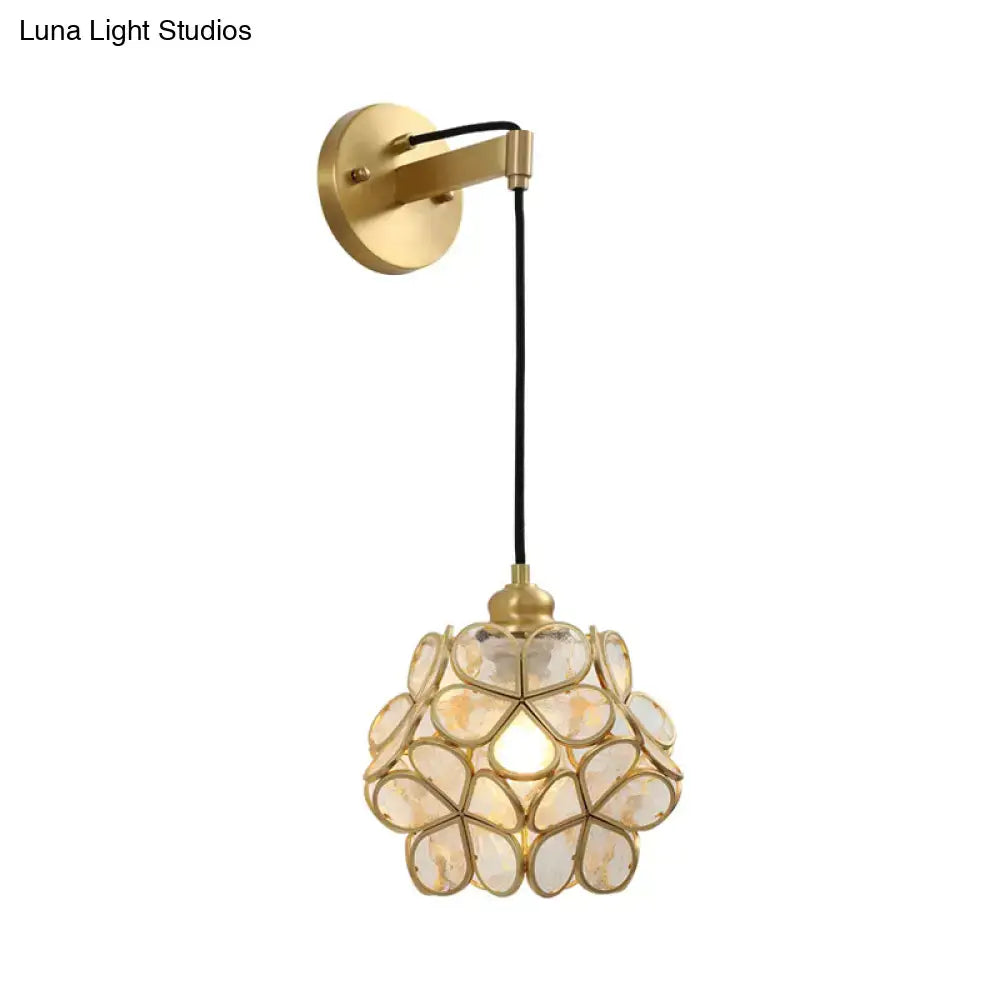 Modernist brass bulb bedside sconce with a gold-toned mount and a light pink clear floral glass shade