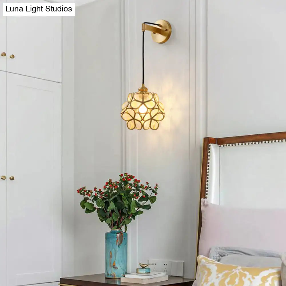 Gold-toned modernist bulb bedside sconce with a delicate light pink clear petal-shaped glass shade in brass
