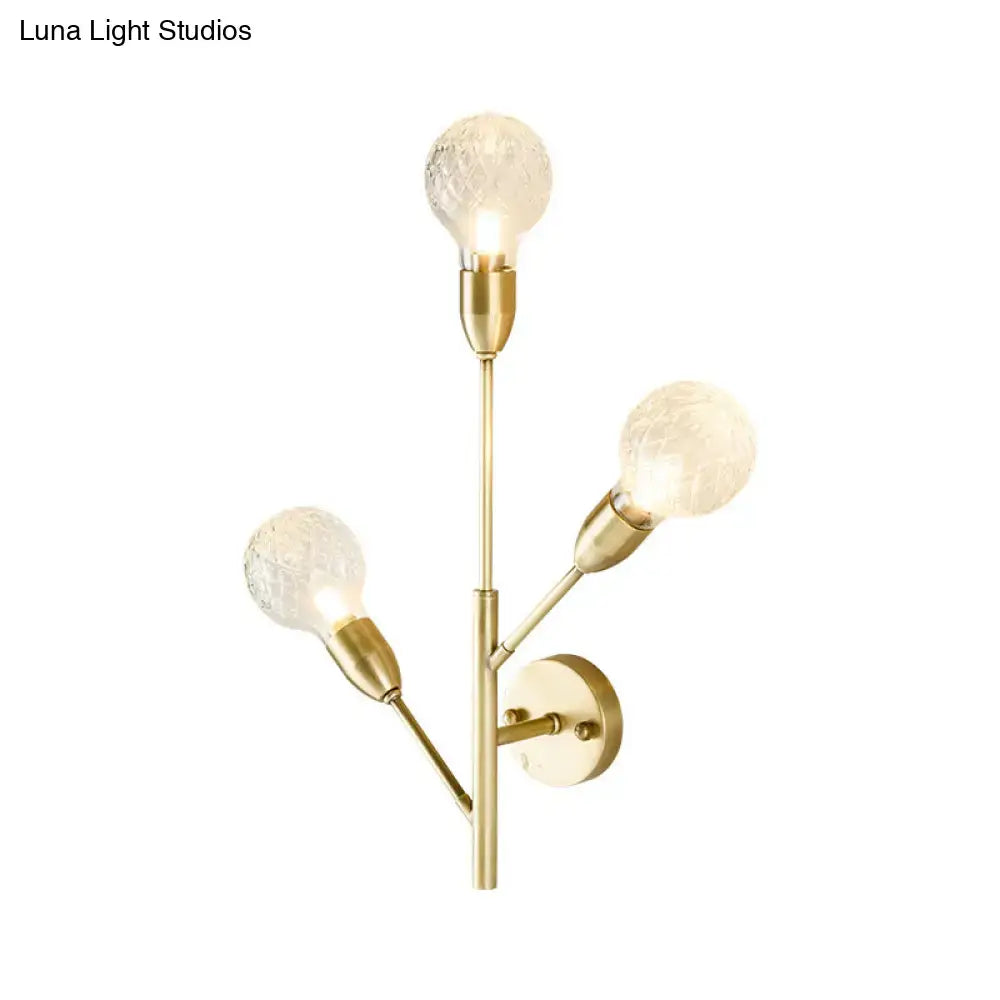 Modernist brass wall mount light fixture with three textured prismatic glass globes for bedroom lighting
