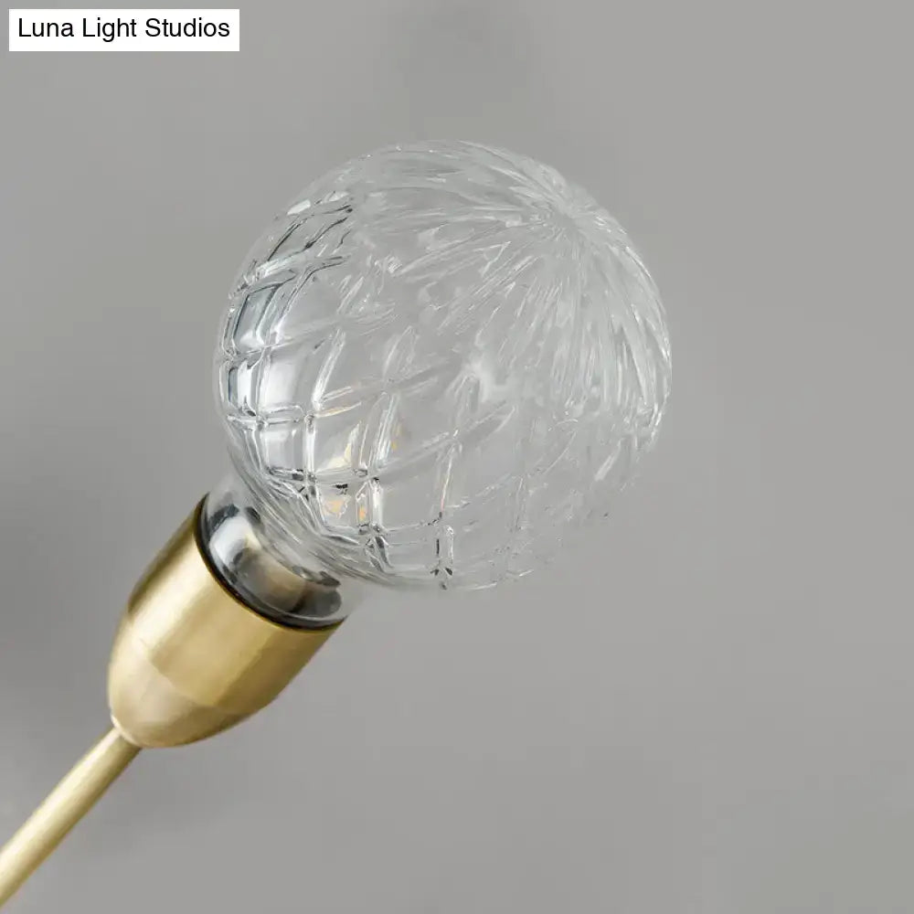 Modernist brass wall mount light fixture featuring a clear faceted prismatic glass bulb with a gold-toned base