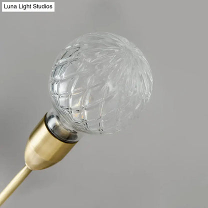 Modernist brass wall mount light fixture featuring a clear faceted prismatic glass bulb with a gold-toned base