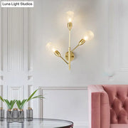 Modernist gold-toned wall mount light fixture with prismatic glass and three frosted bulbs for bedroom use