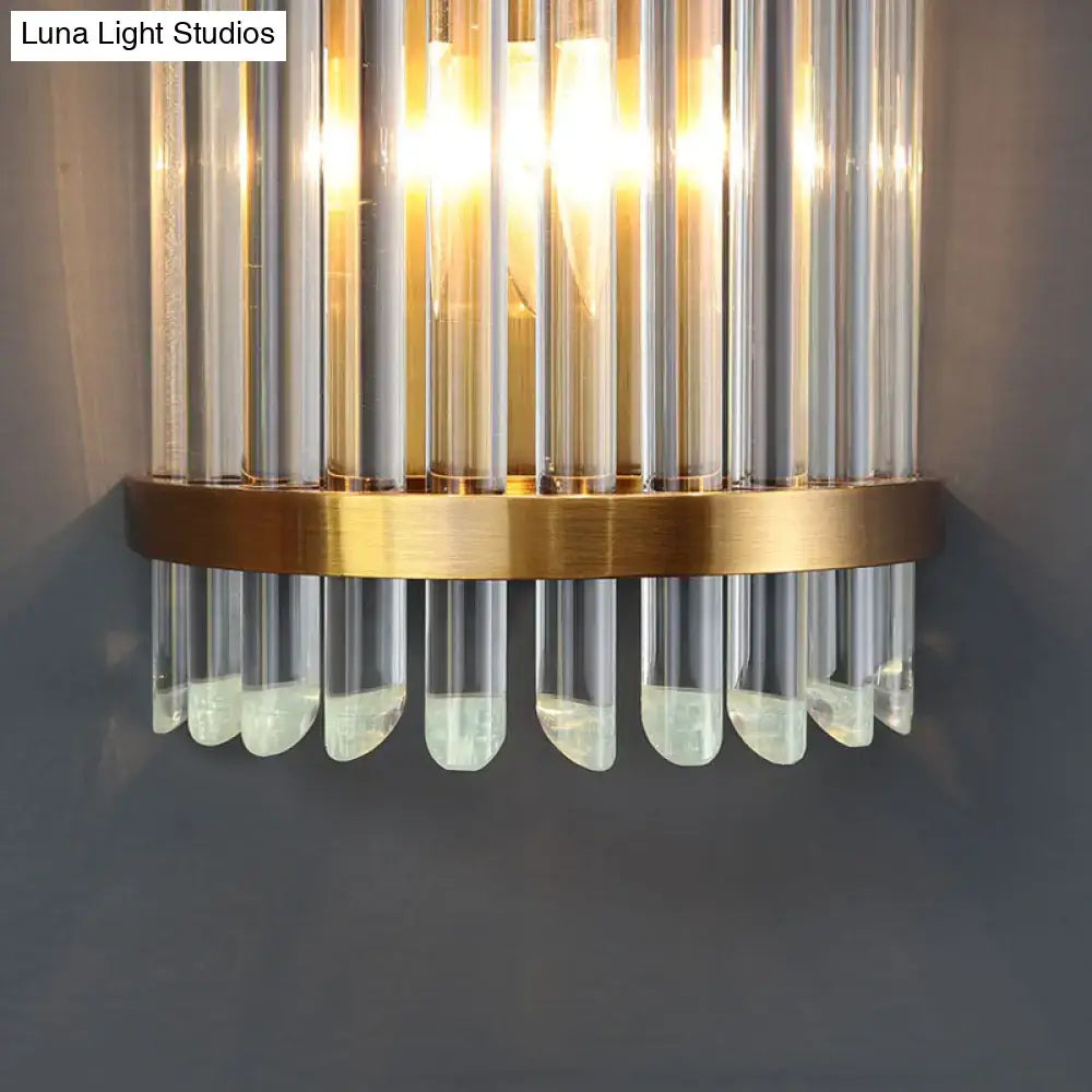 A modernist clear crystal wall sconce with vertical glass tubes and gold finish for elegant living room lighting