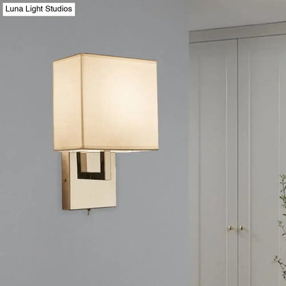 Modernist gold and beige sconce light fixture with square off-white fabric shade and polished brass base for bedroom wall light