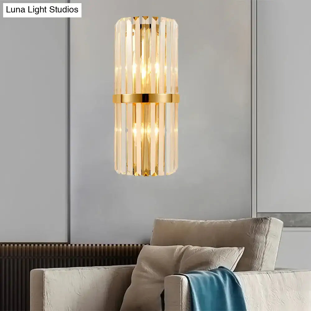Modernist gold and clear crystal cylinder wall lighting features a gold-toned cylindrical wall lighting fixture with vertical crystal rods and brass band