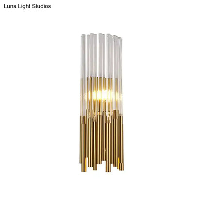 Modernist gold and clear cylinder wall light fixture with vertical glass tubes and warm glowing light for bedroom sconce