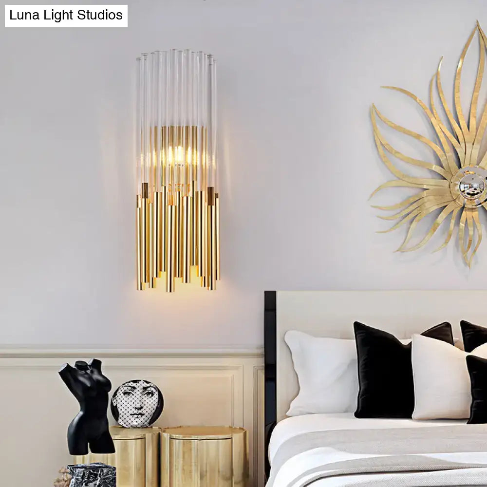 Modernist gold and clear cylinder wall light fixture with vertical glass tubes and warm glow for bedroom sconce