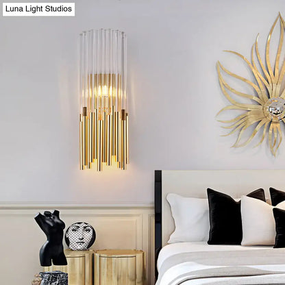 Modernist gold and clear cylinder wall light fixture with vertical glass tubes and warm glow for bedroom sconce
