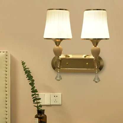 Modernist gold-toned crystal wall sconce with two white pleated lampshades for living room lighting