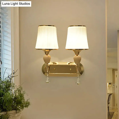Modernist gold crystal wall sconce with two cream pleated lampshades and crystal droplets for living room use