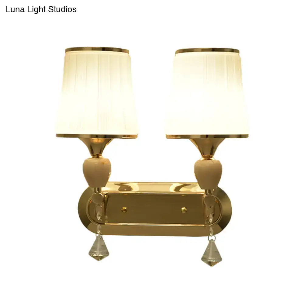 Modernist gold wall sconce with two cream pleated shades and crystal teardrop pendants for living room lighting