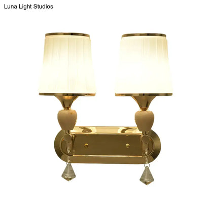 Modernist gold wall sconce with two cream pleated shades and crystal teardrop pendants for living room lighting