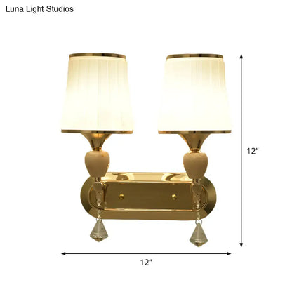 Modernist gold crystal wall sconce with two cream pleated shades and teardrop pendants for living room use