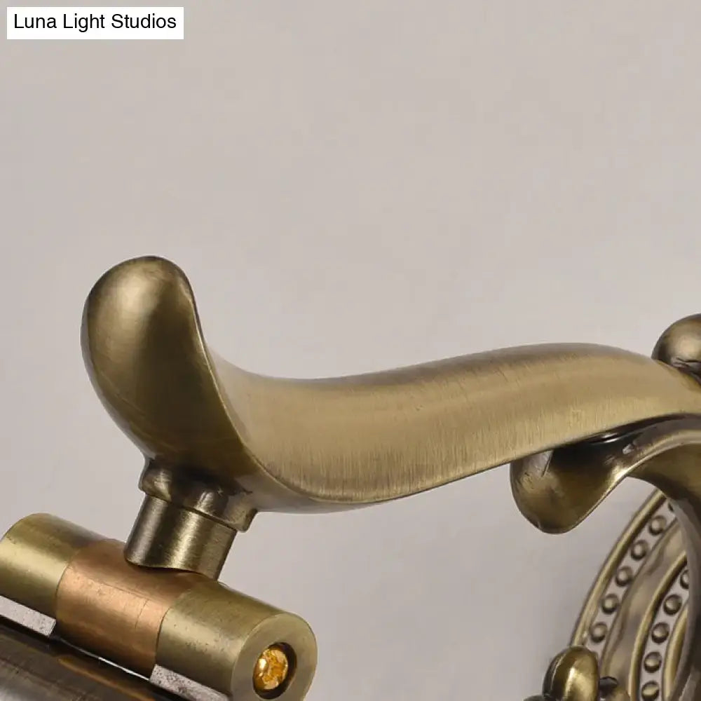 Antique brass-finished door handle with ornate curved design and beaded accents paired with modernist gold linear metallic vanity wall light