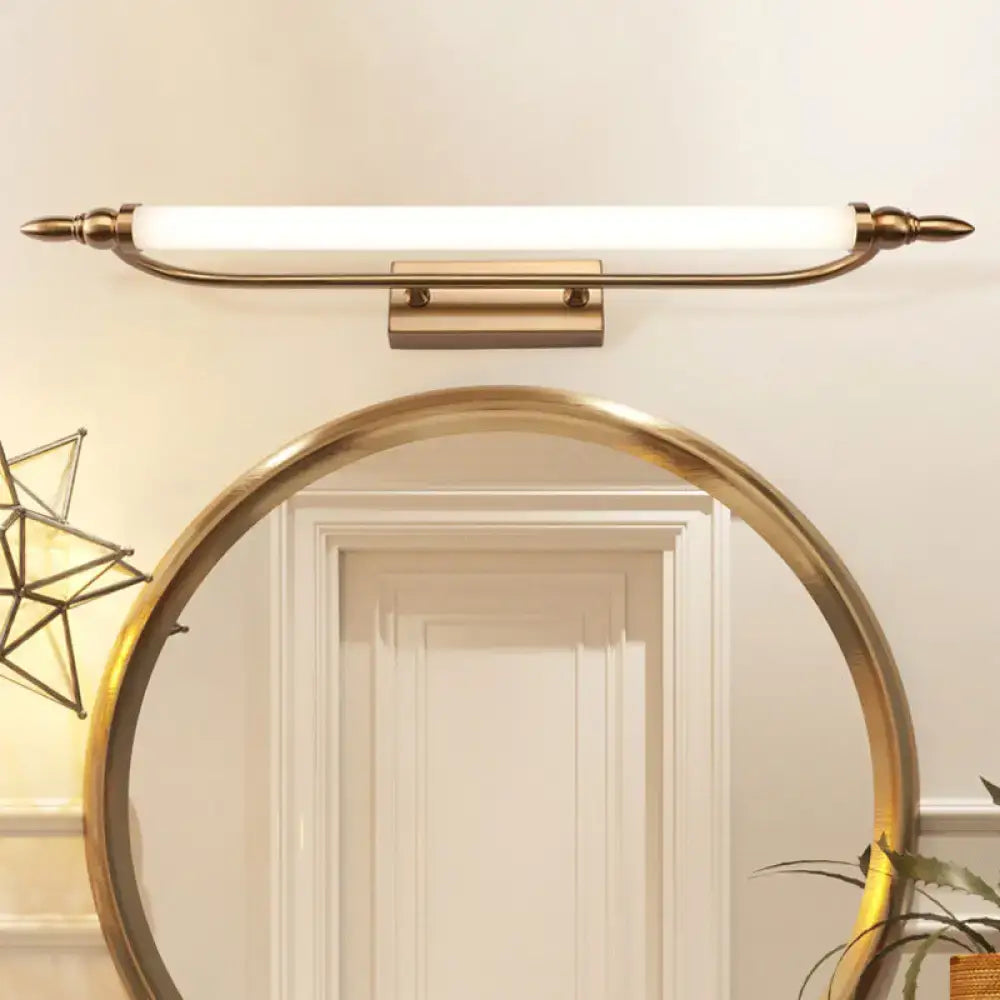 Gold-toned modernist tube metal vanity wall light with frosted glass diffuser and ornate finials for bathroom use
