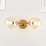 Modernist gold wall lamp with two frosted glass shades for living room featuring a gold-toned wall sconce design