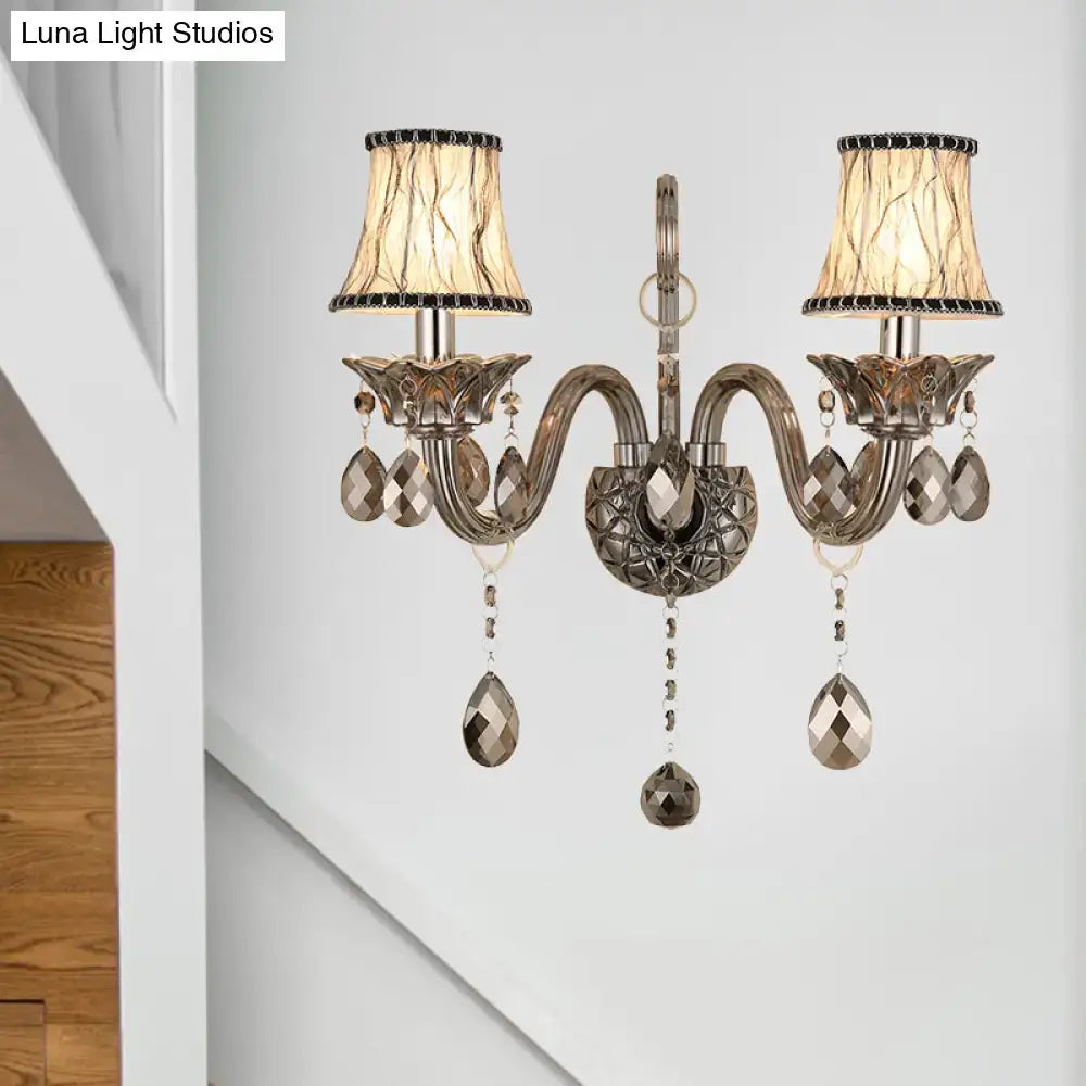 Antique silver two-light wall sconce with smoke grey crystal droplets and beige lampshades for living room wall mounted lighting