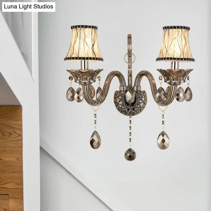Antique silver two-light wall sconce with smoke grey crystal droplets and beige lampshades for living room wall mounted lighting