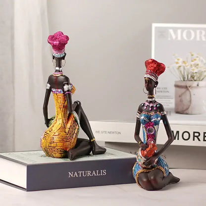 Two ornate dark-skinned black women resin art figures with glittery pink and red headdresses for decorbites black women decor